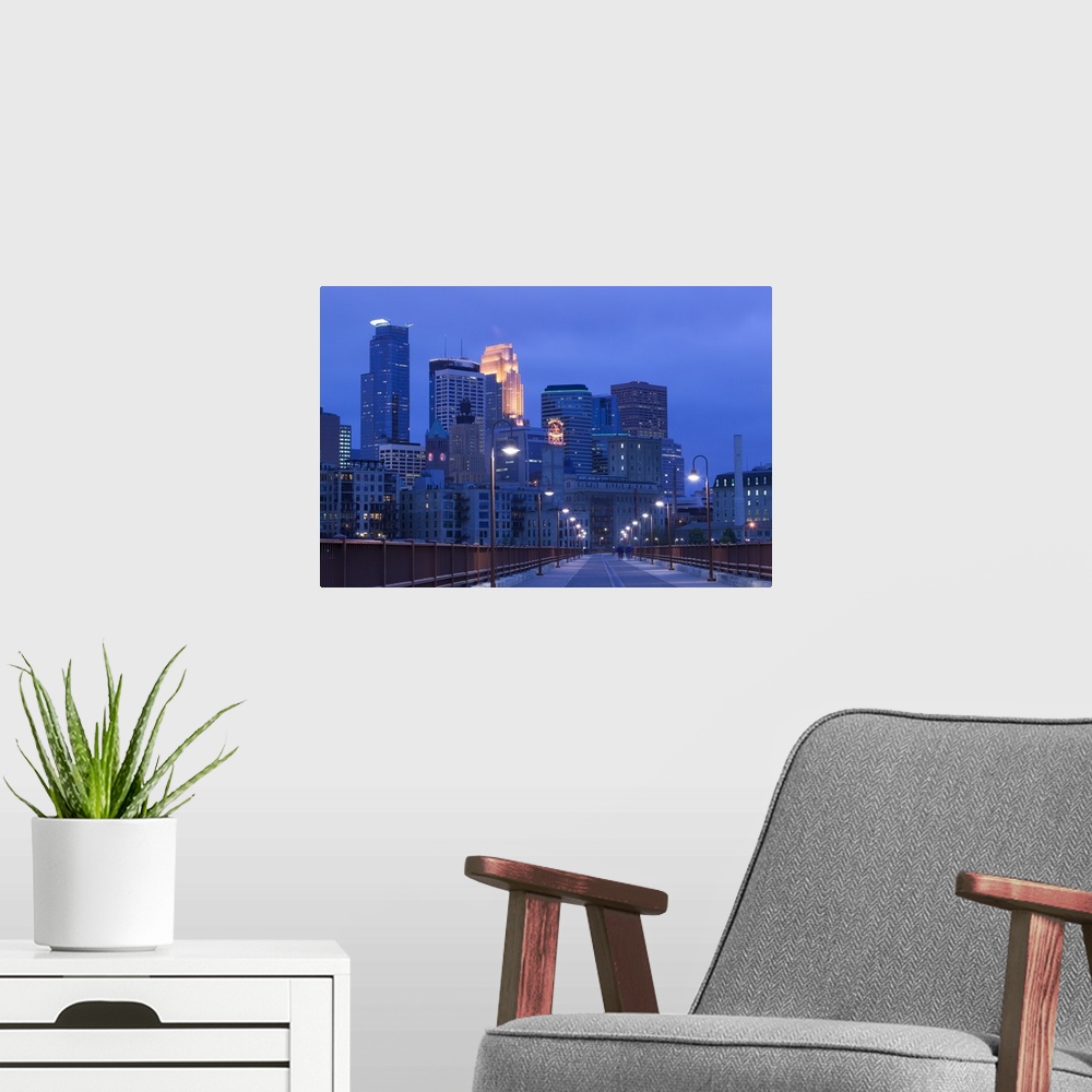 A modern room featuring Giant photograph taken of skyscrapers filling the Minneapolis skyline at night.  The light posts ...