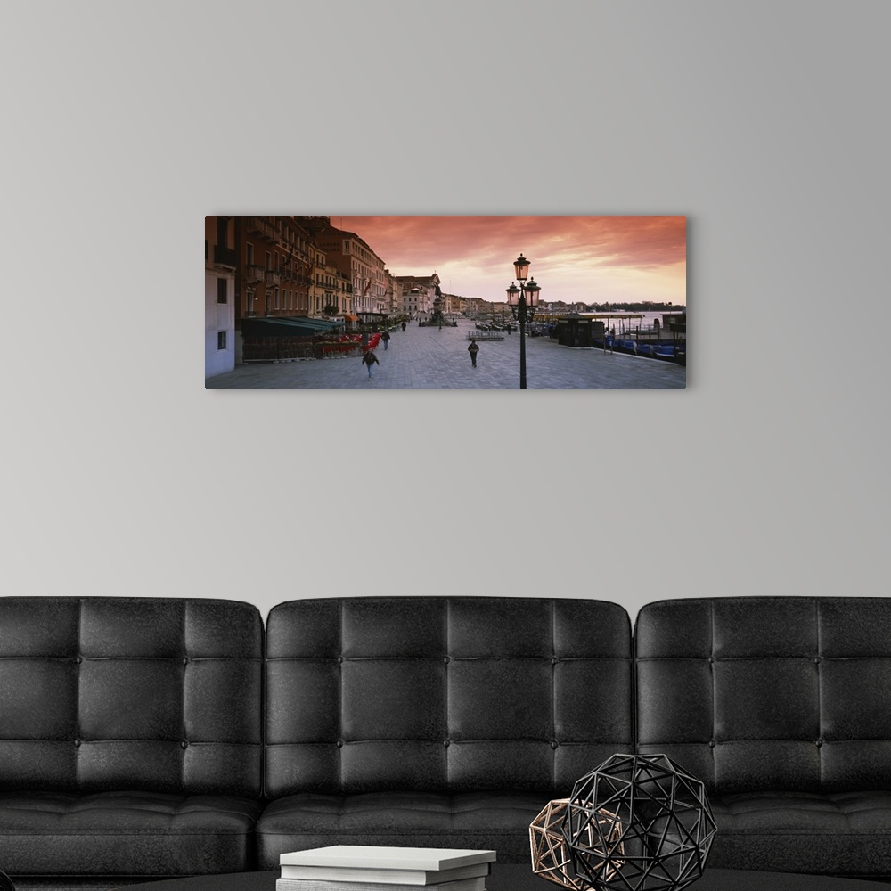 A modern room featuring Panoramic photo of people walking on the promenade along the waterfront at sunrise in Venice, Italy.
