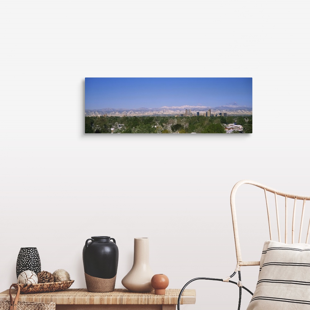 A farmhouse room featuring The city of Denver is photographed from a distance over trees and homes. Mountains are pictured f...