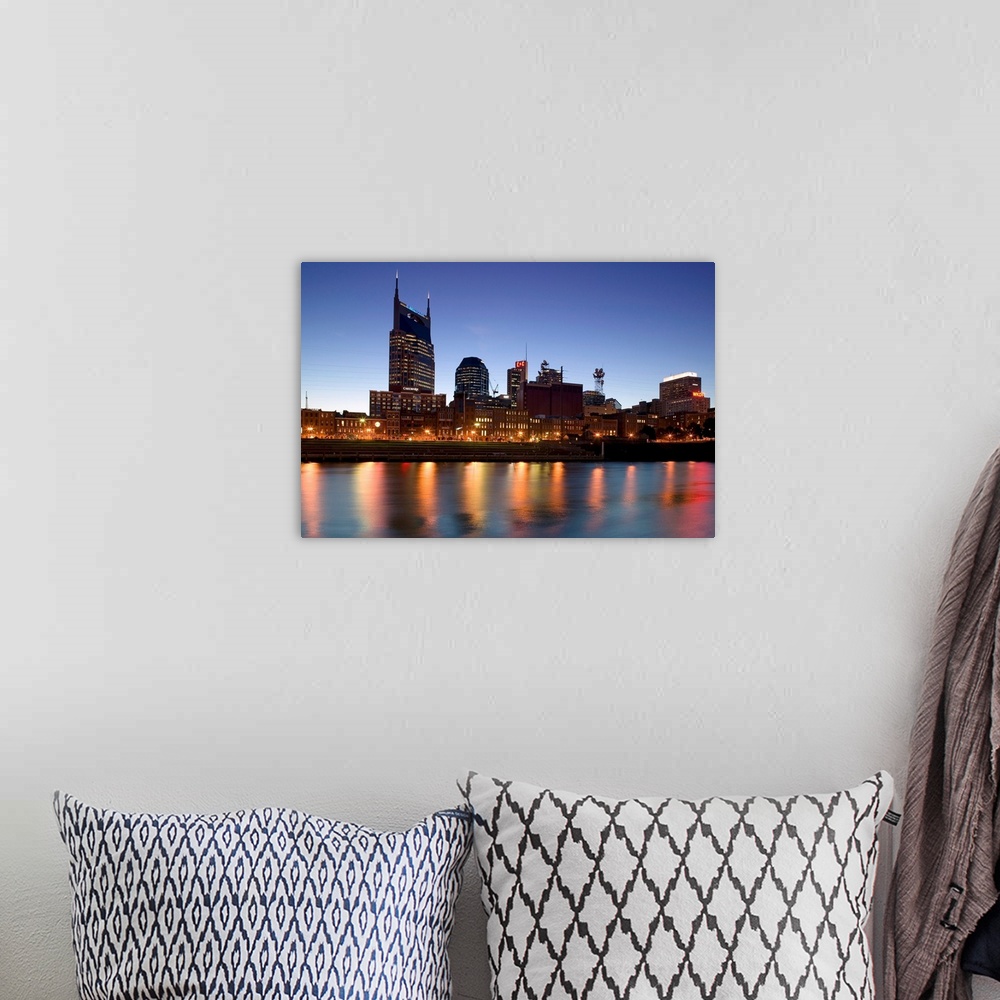 A bohemian room featuring This photograph city skyline lit up in the early twilight and the city lights reflect in the water.