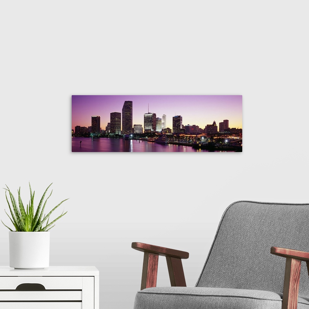 A modern room featuring Panoramic photo of the city skyline lighting up as the sun sets  in Miami, Florida.