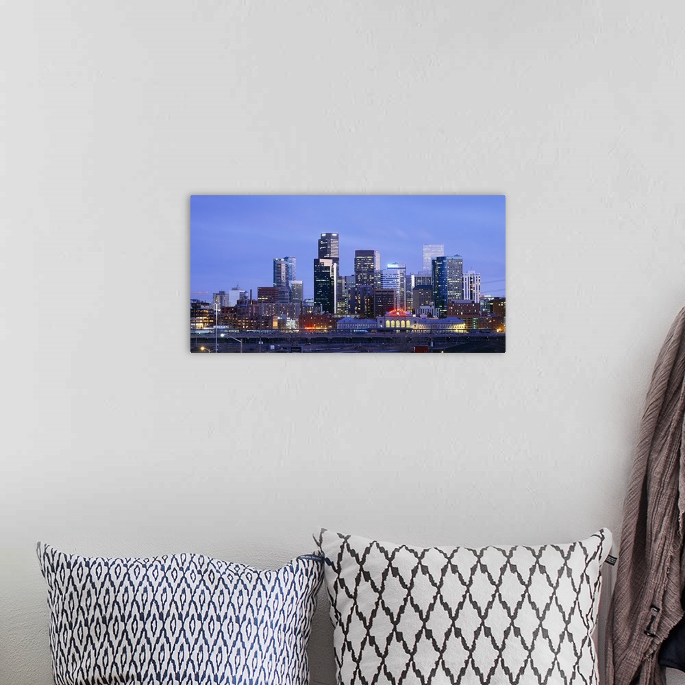 A bohemian room featuring A large panoramic piece of a photograph of the Denver skyline with the buildings lit up during su...