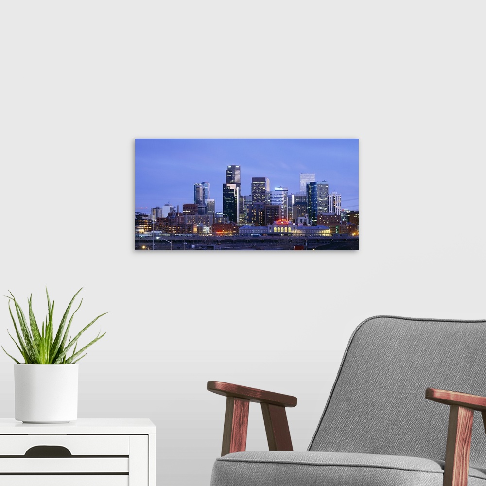 A modern room featuring A large panoramic piece of a photograph of the Denver skyline with the buildings lit up during su...