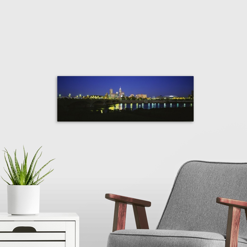 A modern room featuring Big panoramic photo on canvas of a lit up city skyline past a bridge over a river.
