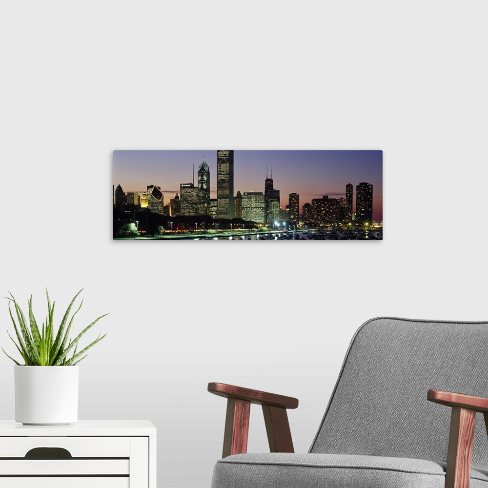 A modern room featuring A wide angle picture taken of the Chicago skyline during sun down with the buildings illuminated.