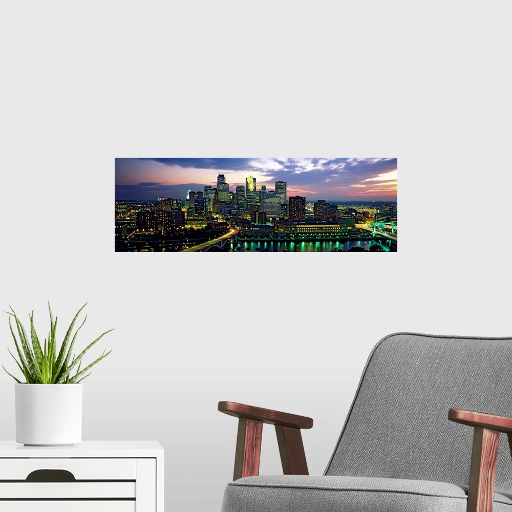 A modern room featuring Wide angle panoramic photograph of Minneapolis skyscrapers at night, beneath a colorful sunset.