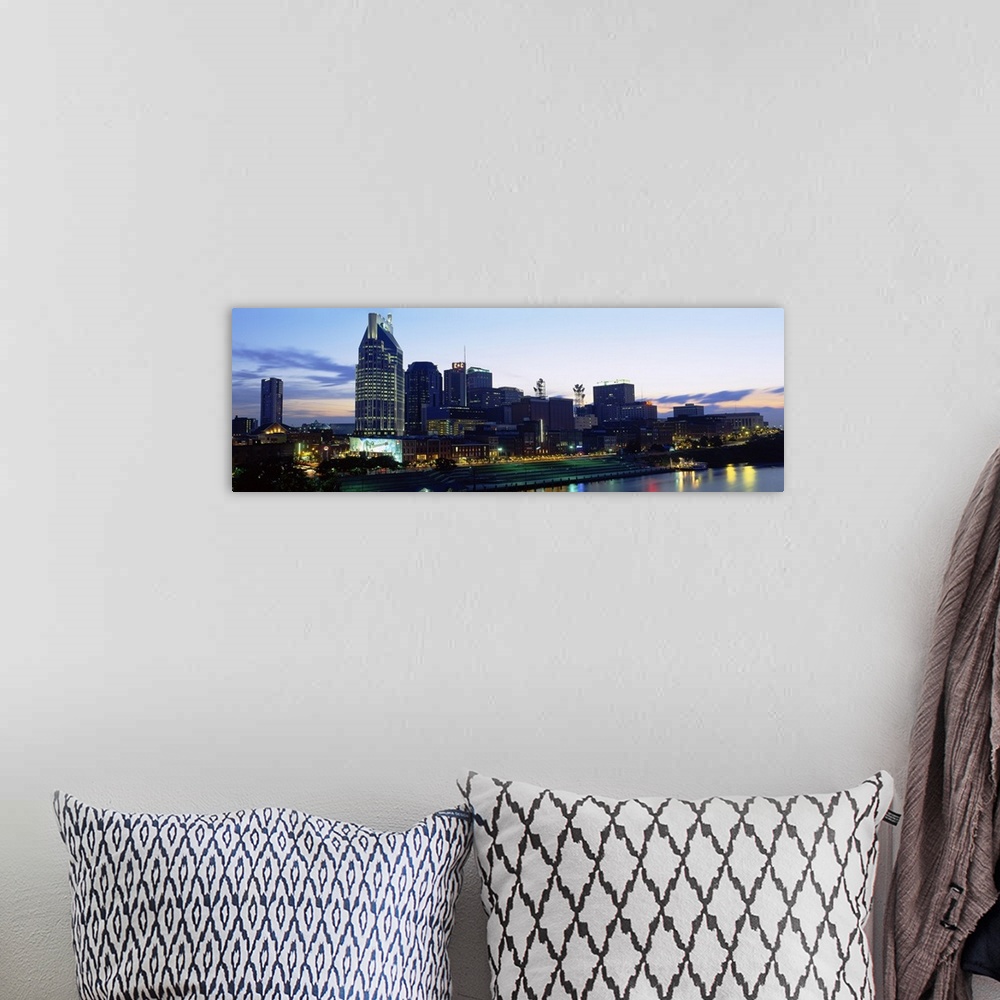 A bohemian room featuring Lights from skyscrapers reflect in the river water in the panoramic photograph of the city skyline.