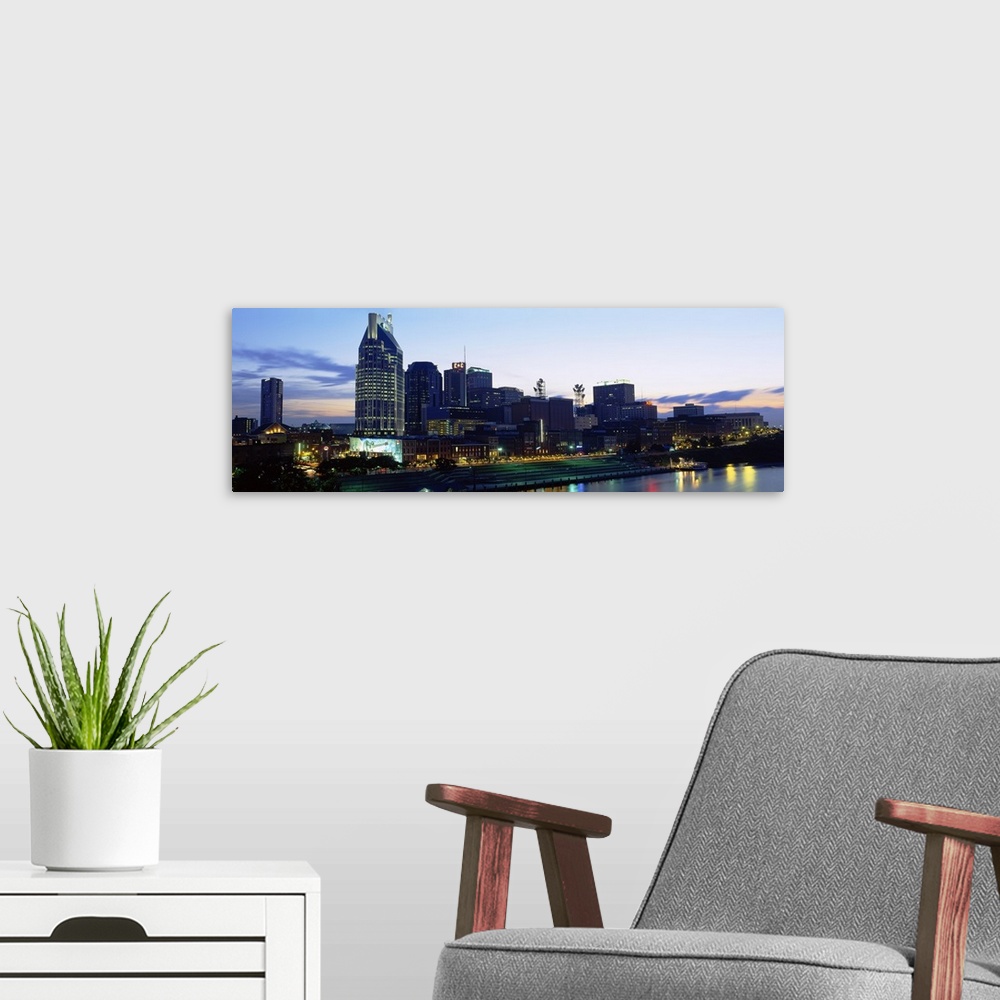 A modern room featuring Lights from skyscrapers reflect in the river water in the panoramic photograph of the city skyline.