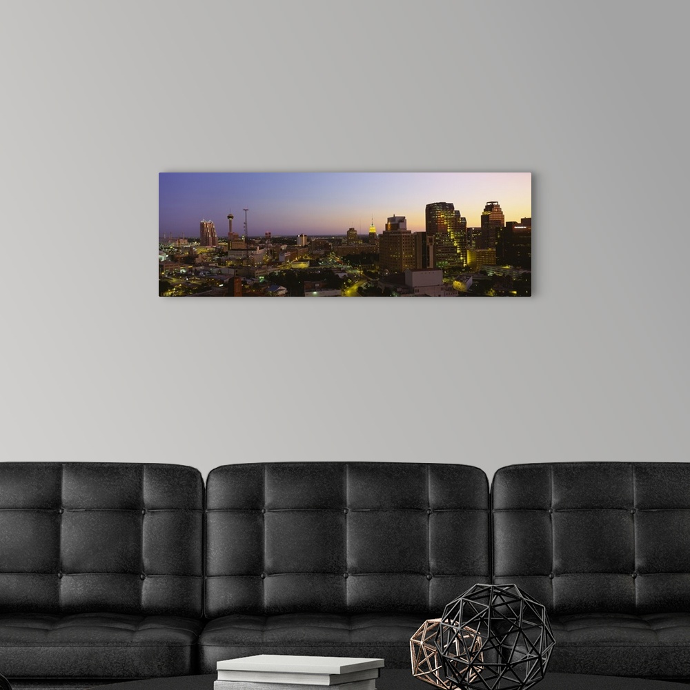 A modern room featuring Big panoramic view of the San Antonio skyline lit up while the sun is setting.