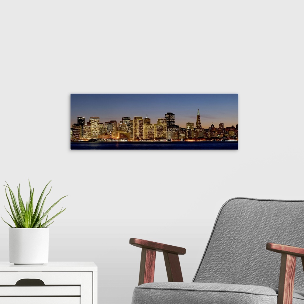 A modern room featuring Panoramic photograph of the San Francisco skyline with all of the buildings lit up under a sky at...