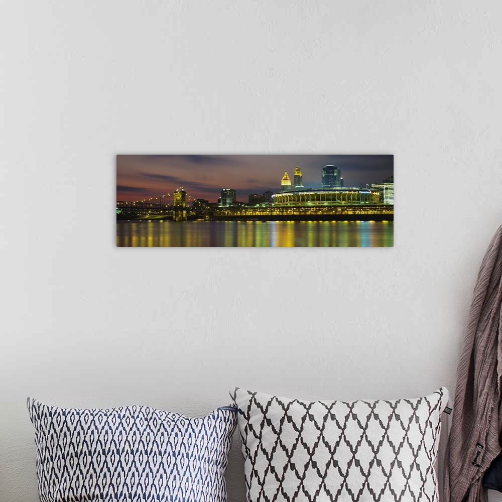 A bohemian room featuring Colorful blurred reflections of a city in a river with a lighted stadium, suspension bridge, and ...