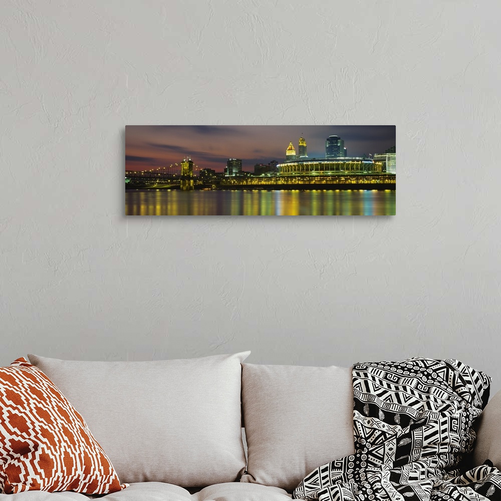 A bohemian room featuring Colorful blurred reflections of a city in a river with a lighted stadium, suspension bridge, and ...