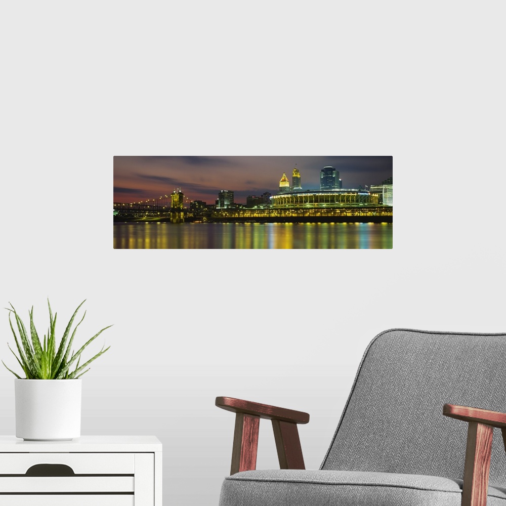 A modern room featuring Colorful blurred reflections of a city in a river with a lighted stadium, suspension bridge, and ...