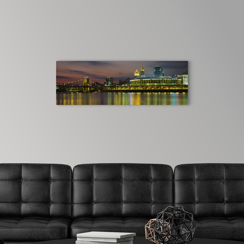 A modern room featuring Colorful blurred reflections of a city in a river with a lighted stadium, suspension bridge, and ...