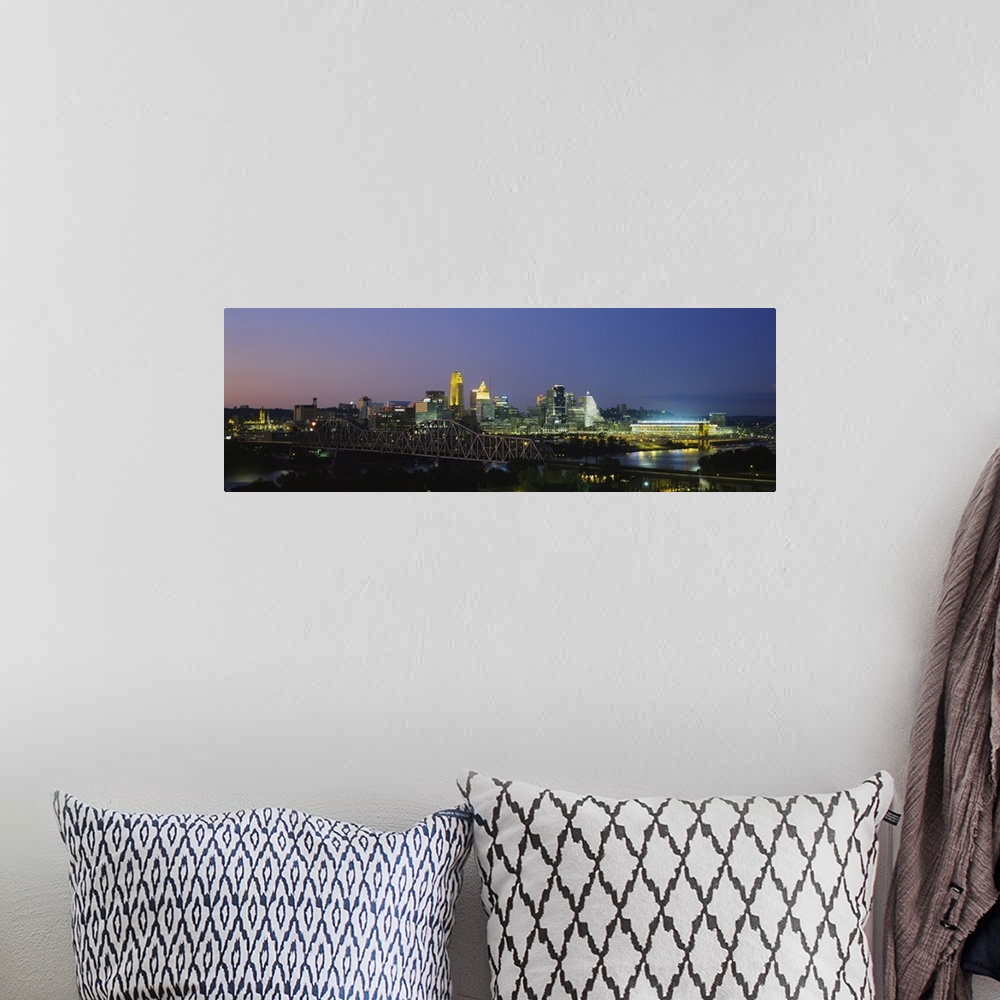 A bohemian room featuring The Cincinnati skyline is photographed in panoramic view and illuminated under a night sky.