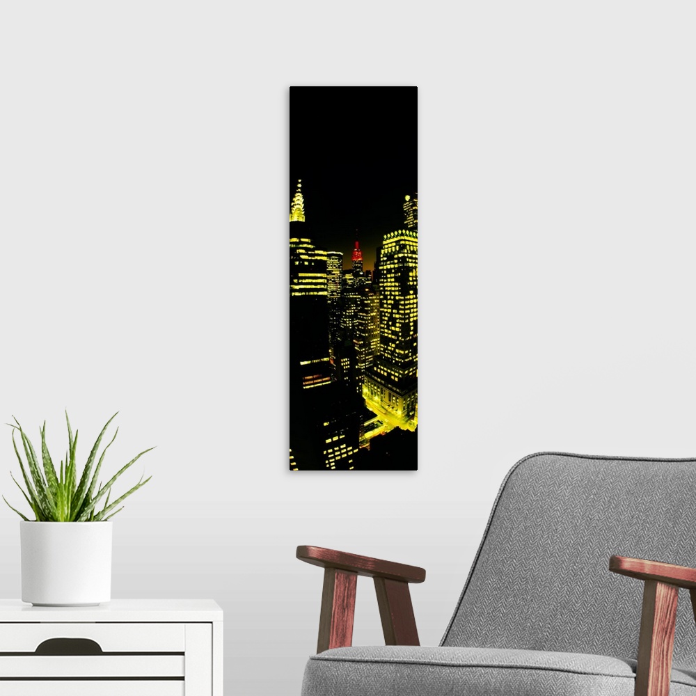 A modern room featuring Vertical panoramic of lit up office buildings in Manhattan with the Empire State building peeking...