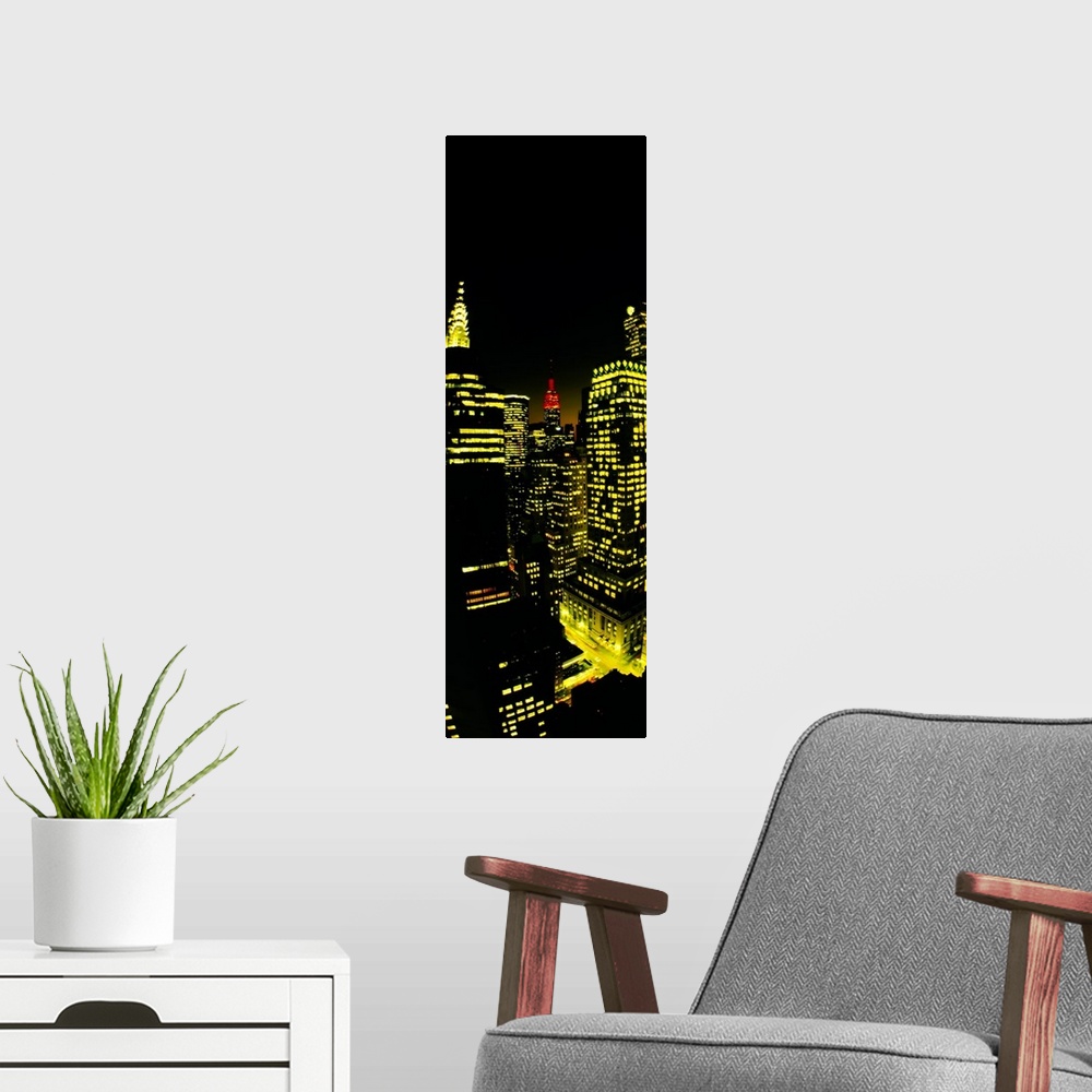 A modern room featuring Vertical panoramic of lit up office buildings in Manhattan with the Empire State building peeking...