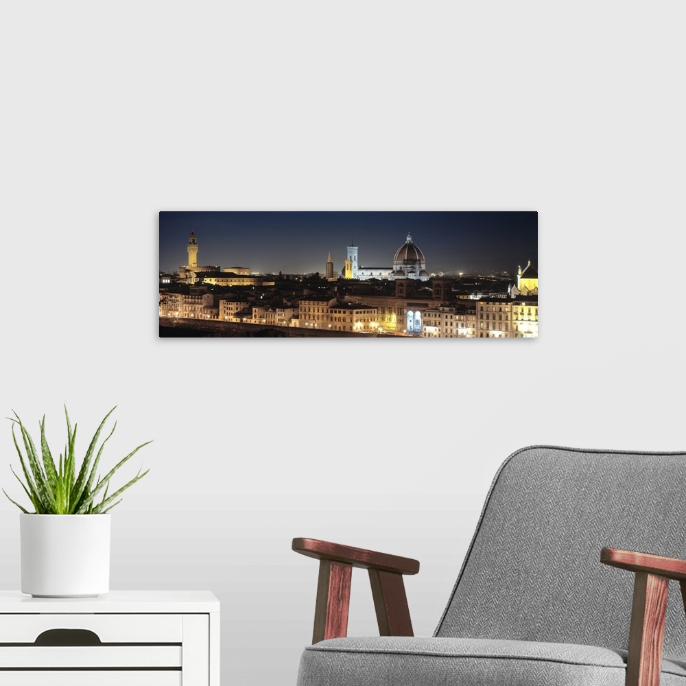 A modern room featuring Long and horizontal photo on canvas of the cityscape of Tuscany illuminated at night.