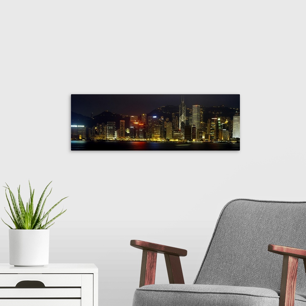 A modern room featuring Panoramic photograph of the Hong Kong skyline, lit up at night, reflecting in the water, in China.