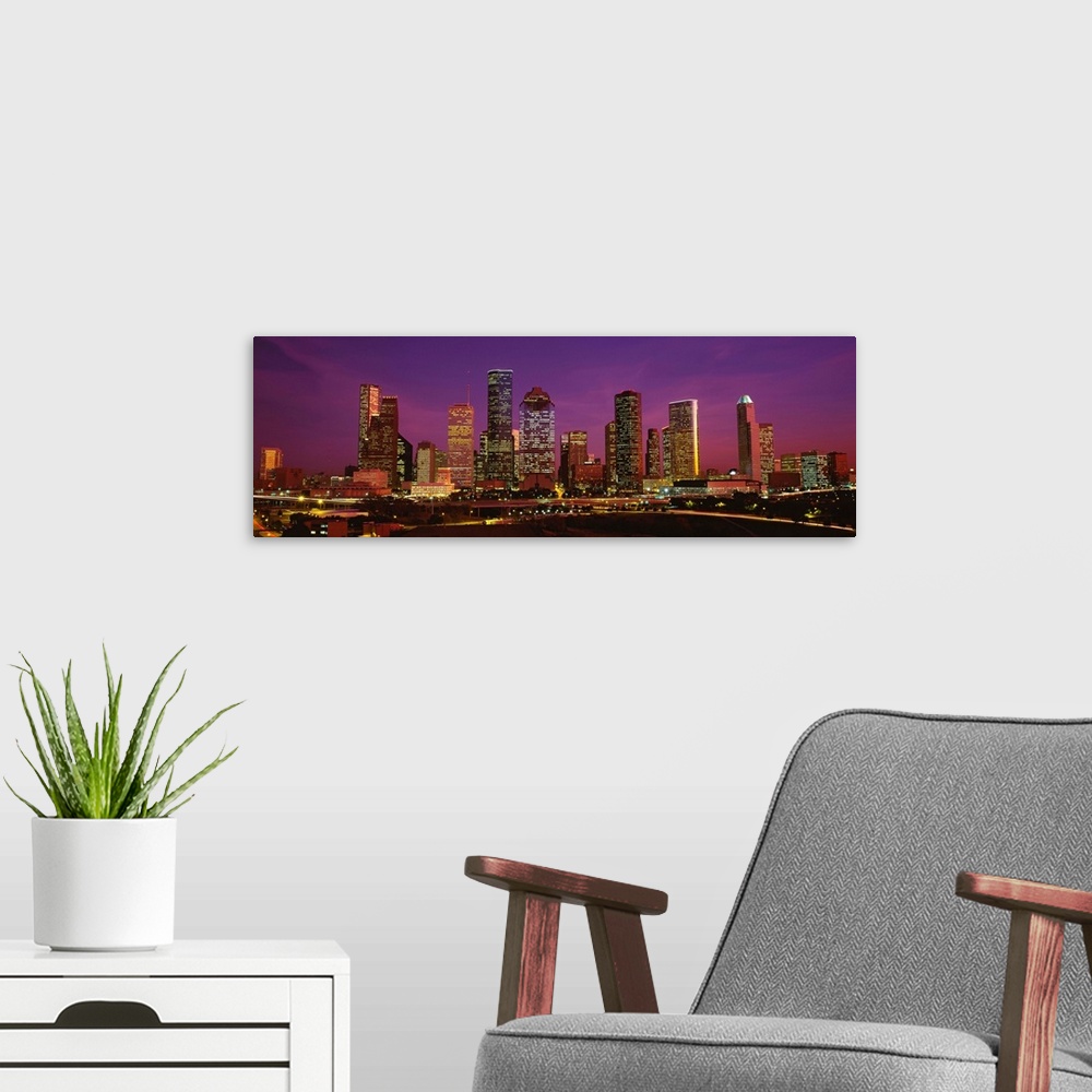 A modern room featuring A panoramic photograph of this skyline and surrounding roads at twilight.
