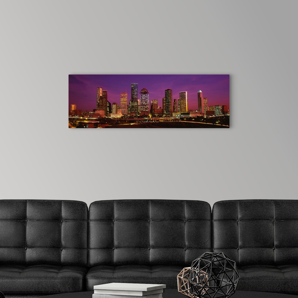 A modern room featuring A panoramic photograph of this skyline and surrounding roads at twilight.