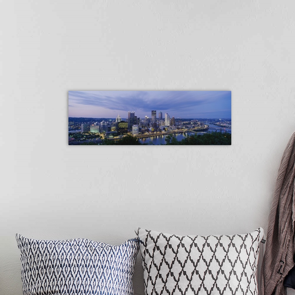 A bohemian room featuring A beautiful photograph of the Pittsburgh skyline lit up at dusk. The river and trees can be seen ...