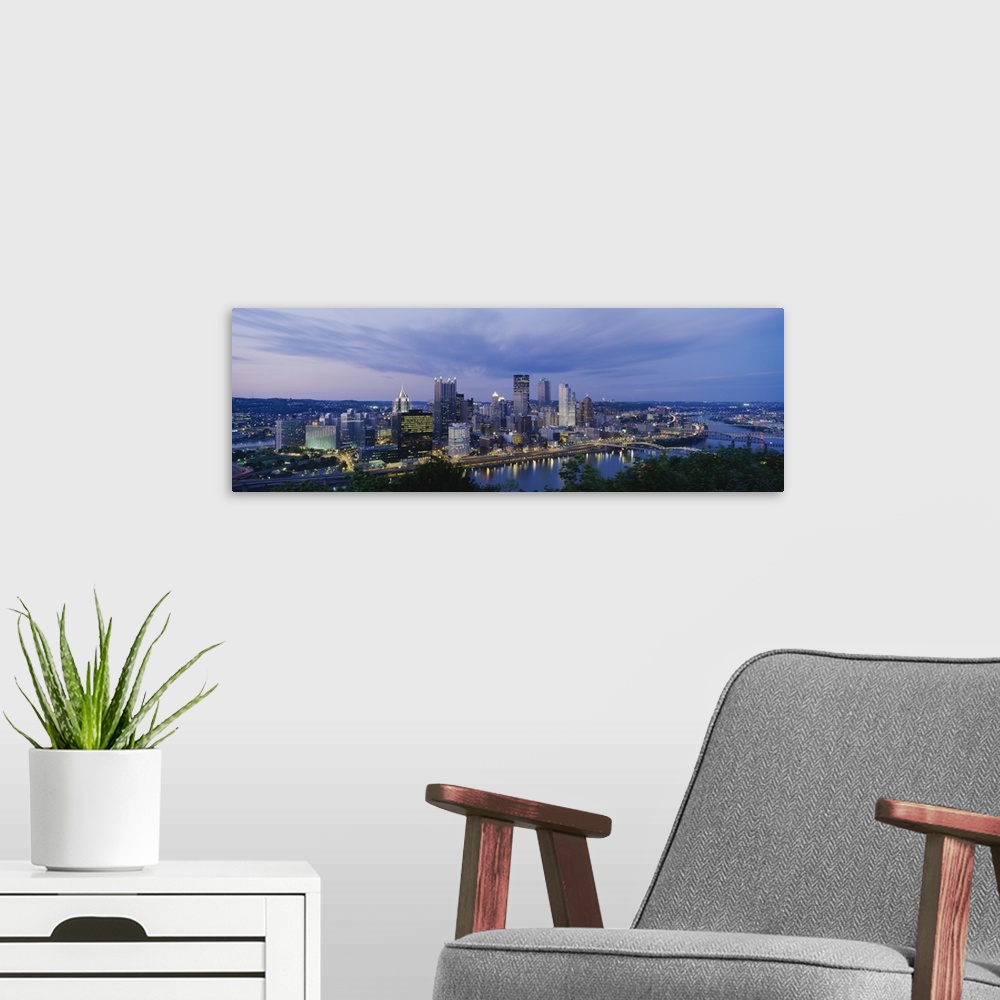 A modern room featuring A beautiful photograph of the Pittsburgh skyline lit up at dusk. The river and trees can be seen ...