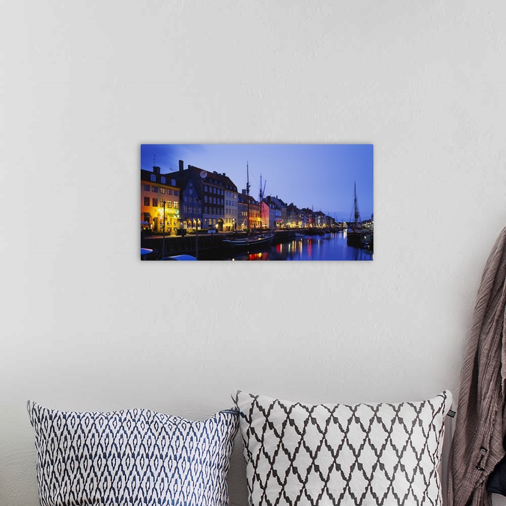 A bohemian room featuring Big canvas photo of buildings along a street following a waterfront with boats lit up at night.