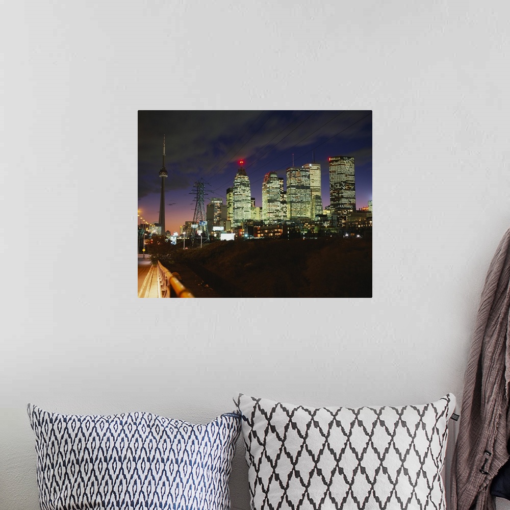 A bohemian room featuring Landscape photograph taken from a street of brightly lit skyscrapers beneath a cloudy sky at nigh...