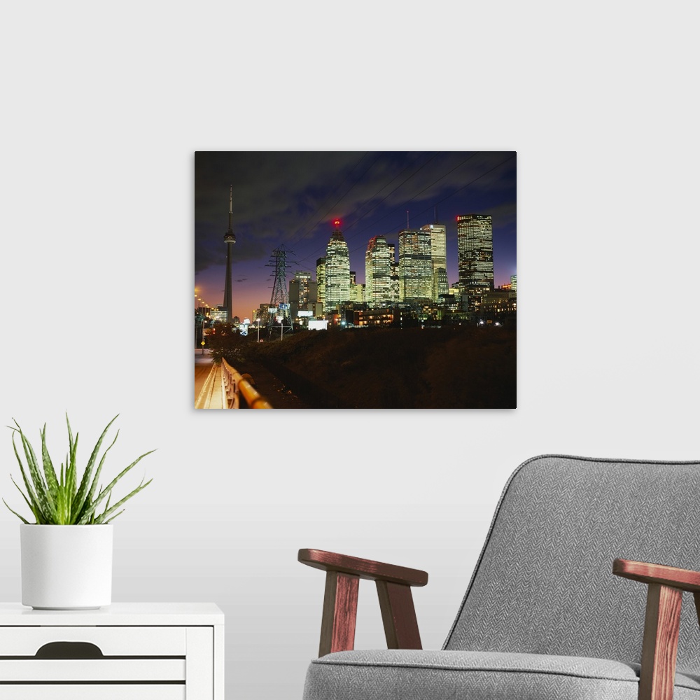 A modern room featuring Landscape photograph taken from a street of brightly lit skyscrapers beneath a cloudy sky at nigh...