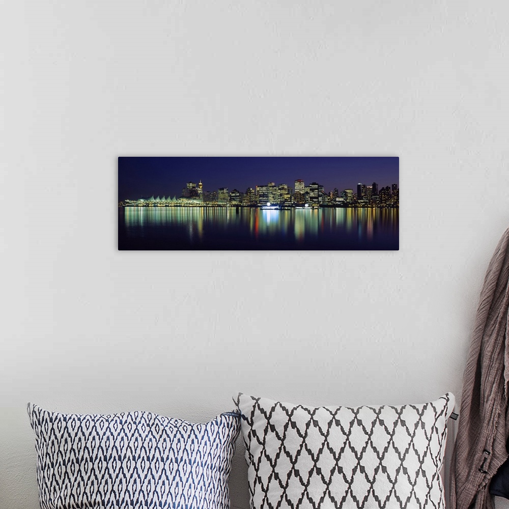A bohemian room featuring The Vancouver skyline is illuminated under a night sky and the lights reflecting in the water.