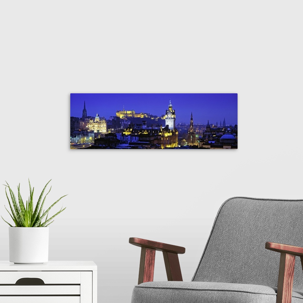 A modern room featuring Panoramic photograph taken of buildings in Scotland lit up at night with a castle shown in the ba...
