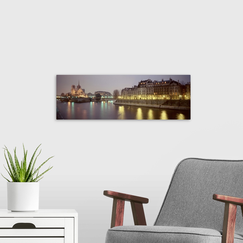 A modern room featuring The lights of the Notre Dame cathedral and other historic buildings reflected in the water on an ...