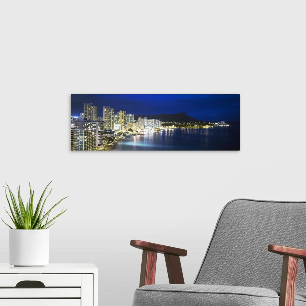 A modern room featuring Panoramic photograph shows an illuminated skyline shining brightly on the coast of an island with...