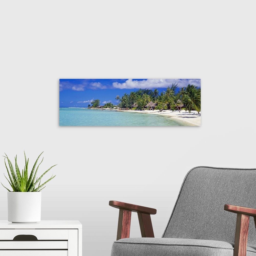 A modern room featuring Panoramic photograph on a big canvas of many bungalows nestled amongst palm trees along the coast...