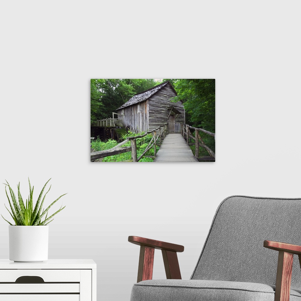 A modern room featuring Picture taken of an old mill that has a small bridge path leading up to and is surrounded by lush...