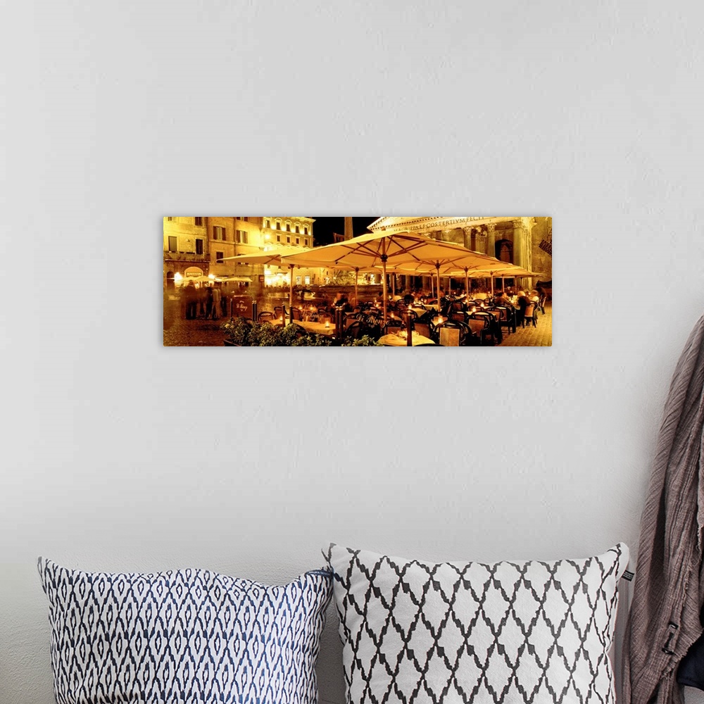 A bohemian room featuring This panoramic photograph captures a rustic cafo in a plaza in the evening light.