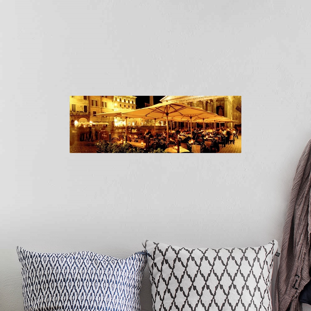 A bohemian room featuring This panoramic photograph captures a rustic cafo in a plaza in the evening light.