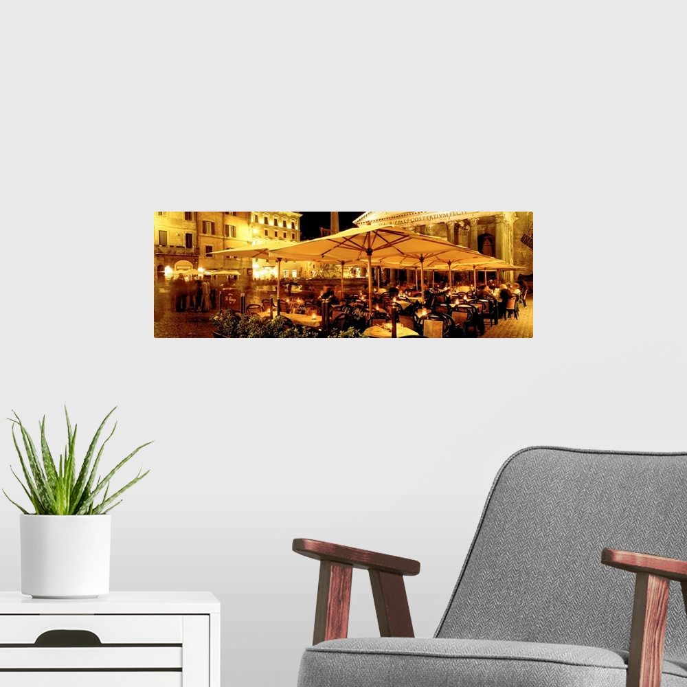 A modern room featuring This panoramic photograph captures a rustic cafo in a plaza in the evening light.