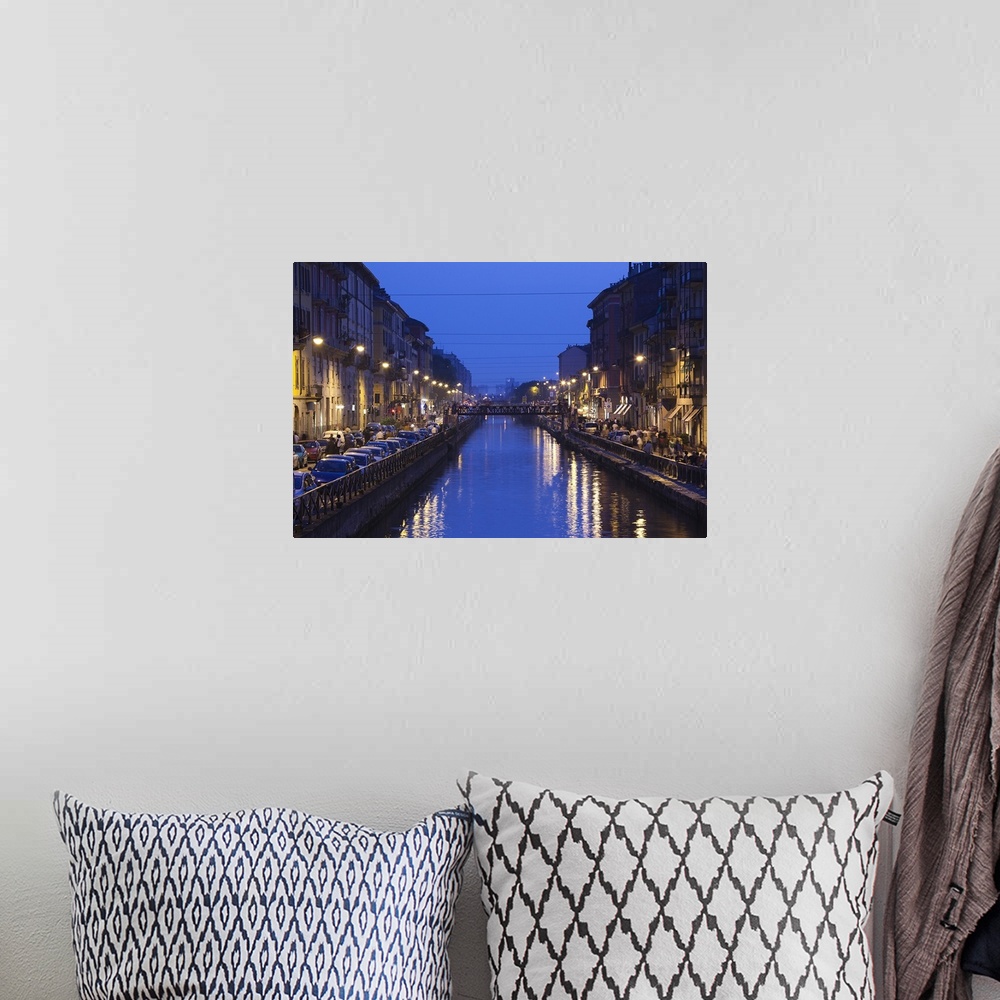 A bohemian room featuring Landscape photograph on giant wall hanging, looking down a canal that is lit from both sides, as ...