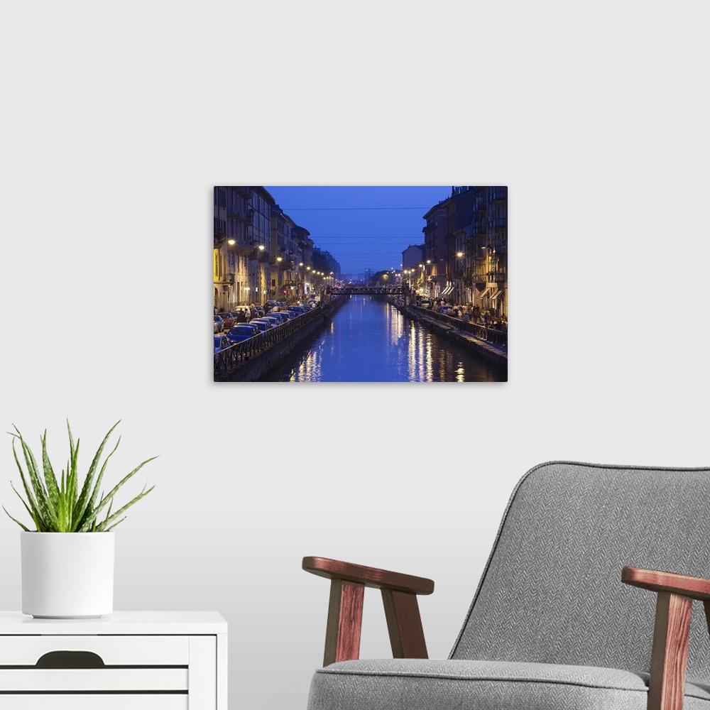 A modern room featuring Landscape photograph on giant wall hanging, looking down a canal that is lit from both sides, as ...