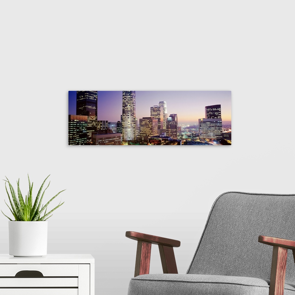 A modern room featuring Wide angle photograph on a big canvas of the brightly lit skyline of Los Angeles, California, at ...