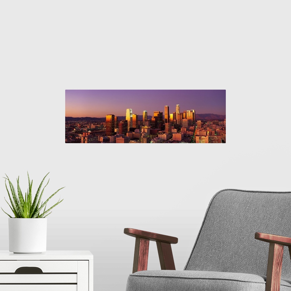 A modern room featuring Panoramic photograph of west coast city skyline at dusk.  The buildings and skyscrapers are lit u...