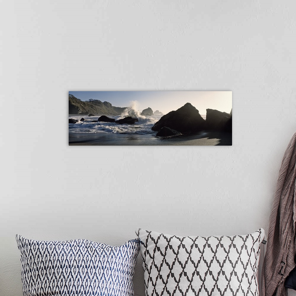 A bohemian room featuring Panoramic photograph of shoreline with huge boulders with ocean waves and spray.