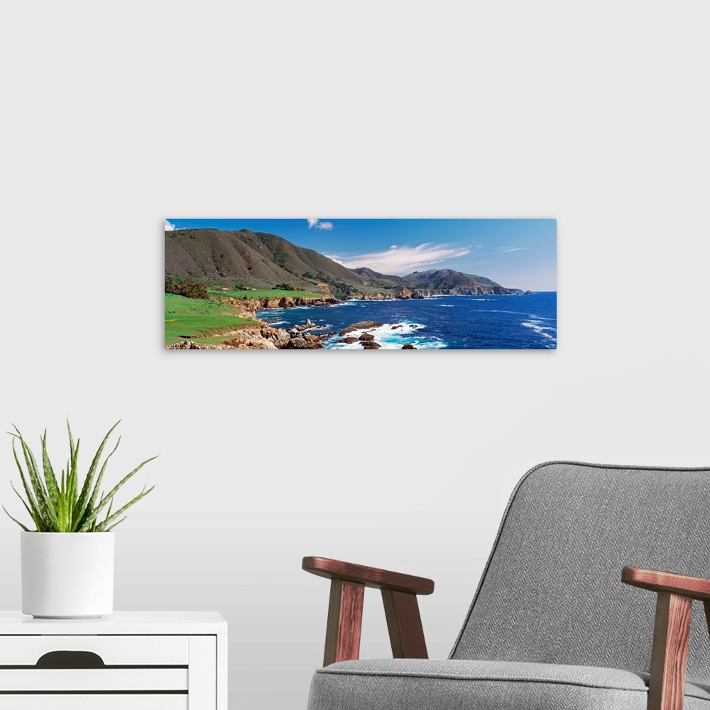 A modern room featuring Wide angle photograph of the coastline in Big Sure, California.  Hills jutting into the blue wate...