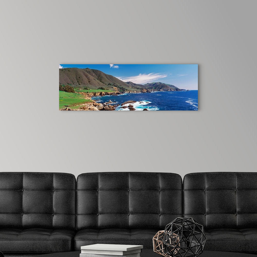 A modern room featuring Wide angle photograph of the coastline in Big Sure, California.  Hills jutting into the blue wate...