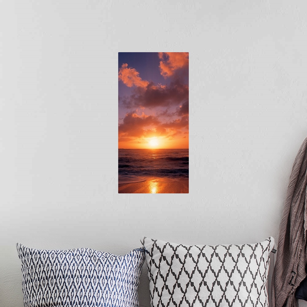 A bohemian room featuring This vertical photograph shows the sun setting at the beach as waves wash against the shore.