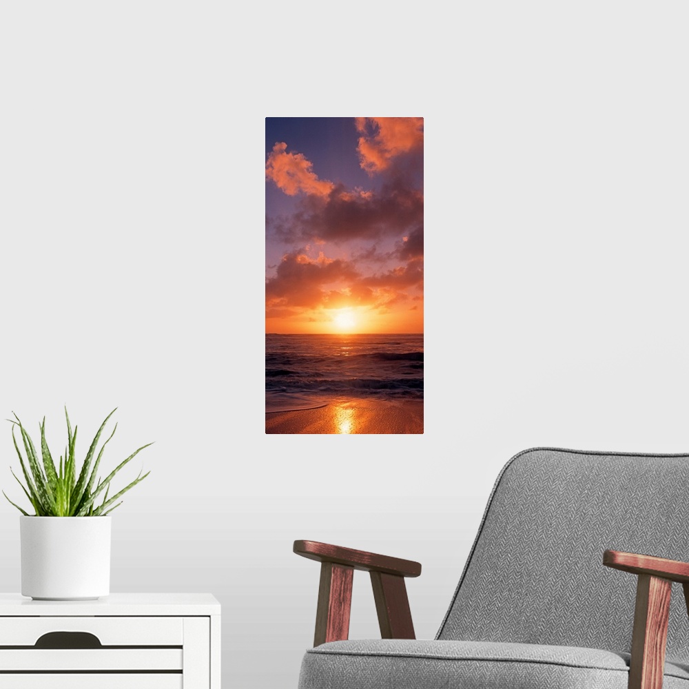 A modern room featuring This vertical photograph shows the sun setting at the beach as waves wash against the shore.