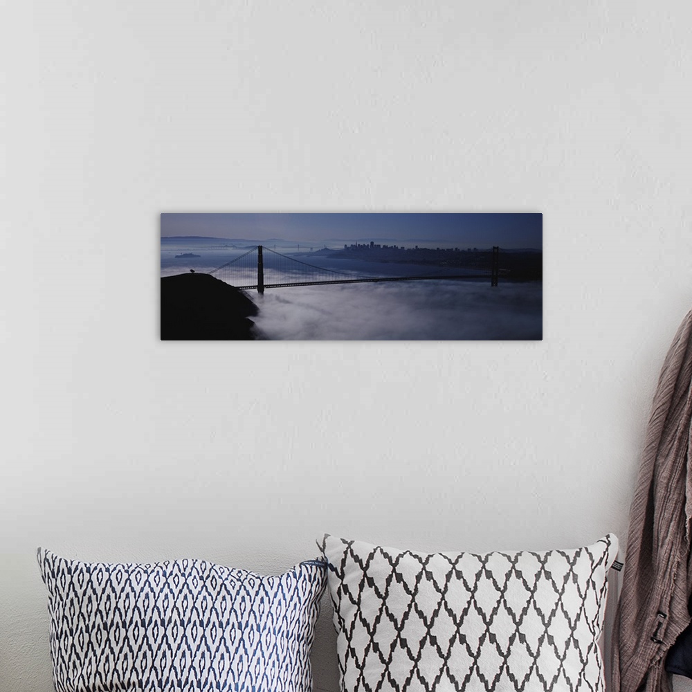 A bohemian room featuring Large panoramic piece of the Golden Gate bridge that has dense fog just under it covering the wat...