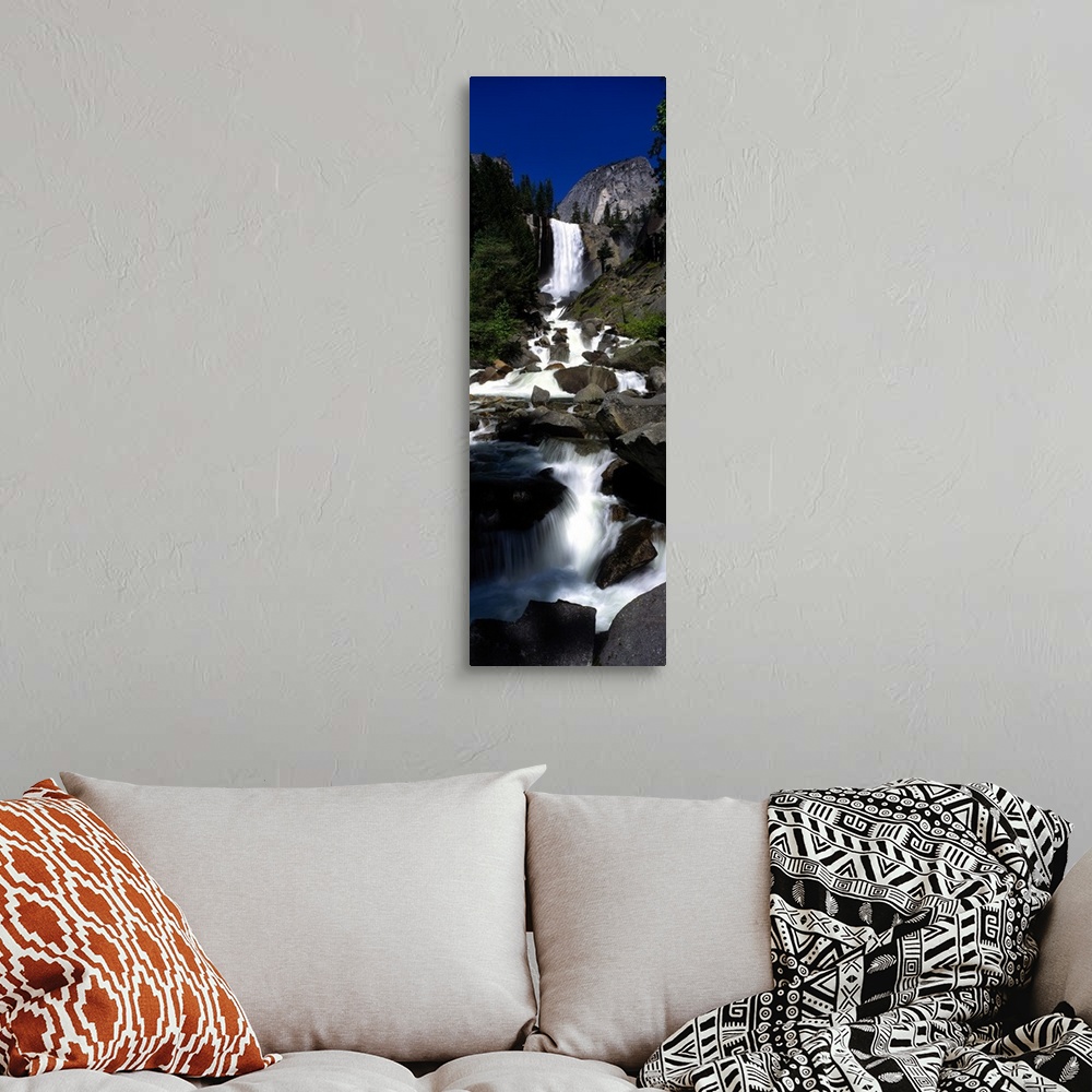 A bohemian room featuring Vertical panoramic photograph of waterfall flowing into a rocky stream surrounded by trees.